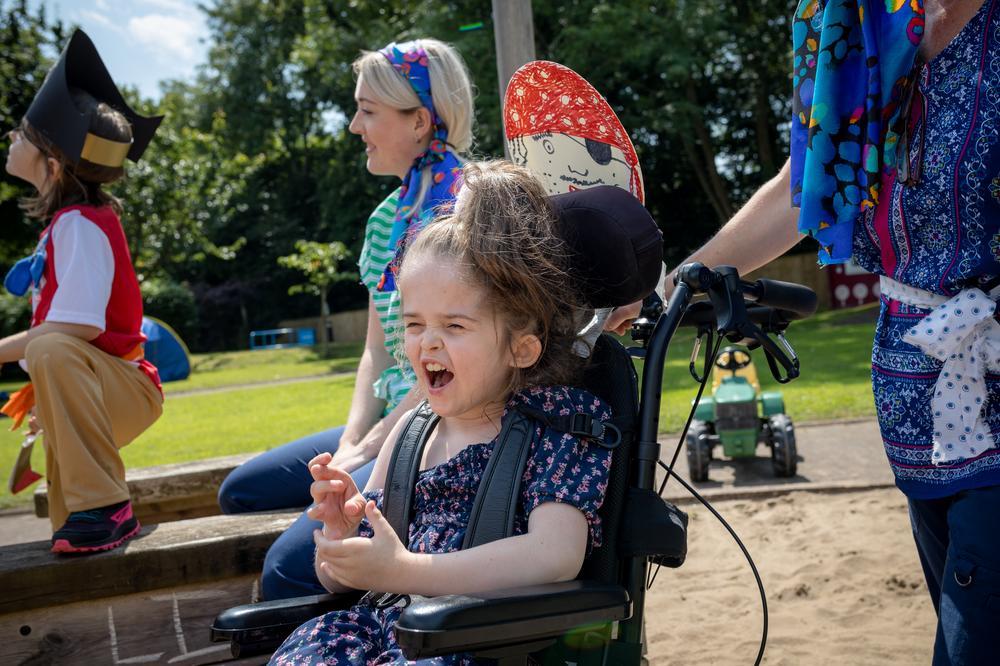 Smiling girl in a wheelchair in a sunny garden